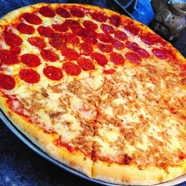 A large pizza, half pepperoni and half cheese, on a pan