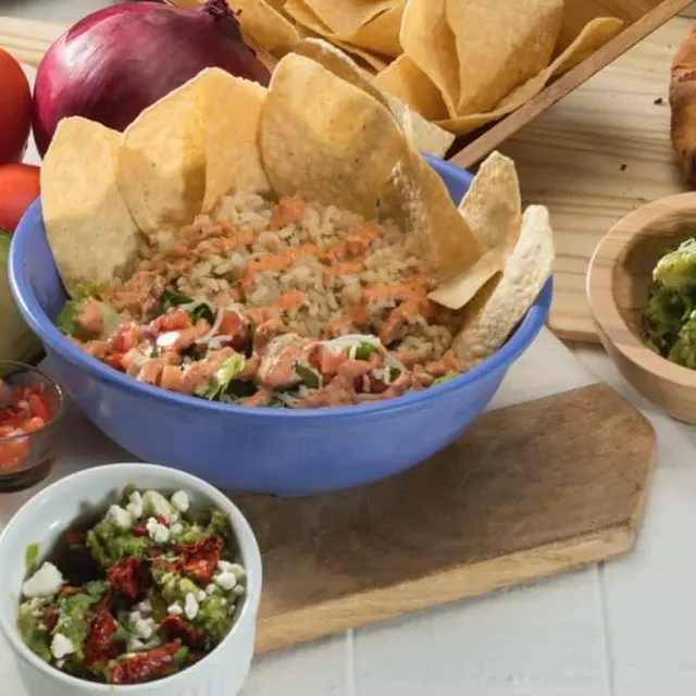A blue bowl of rice with salsa, ringed with tortilla chips